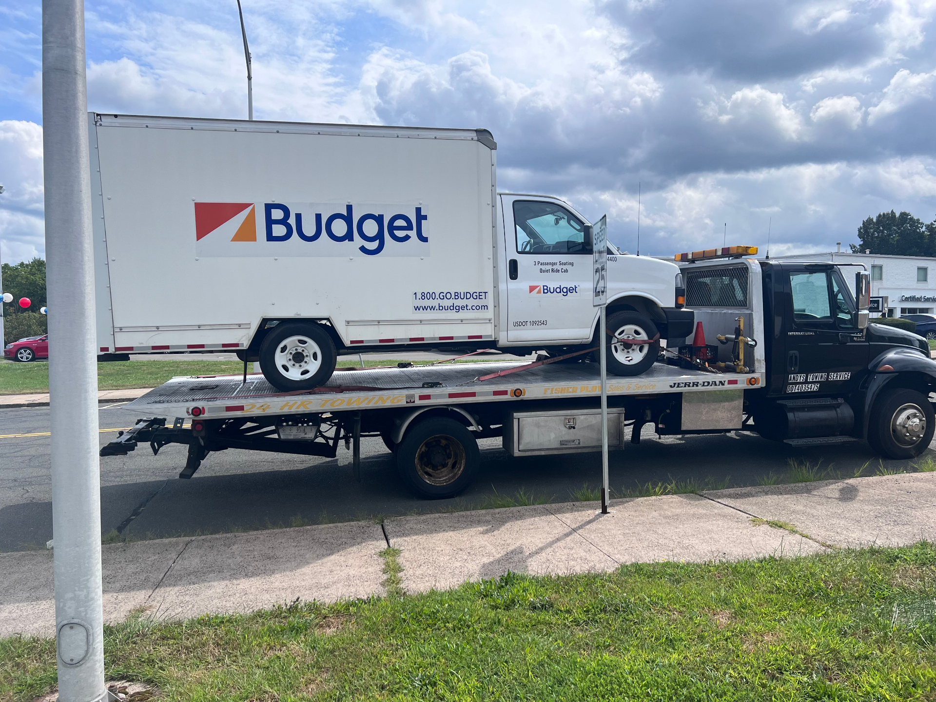 Andy's Towing flatbed hauling a Budget rental truck